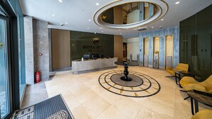 A modern lobby with a reception desk, seating area, and a circular decorative floor pattern. - BENESTA GUEST TEORI (Istanbul)