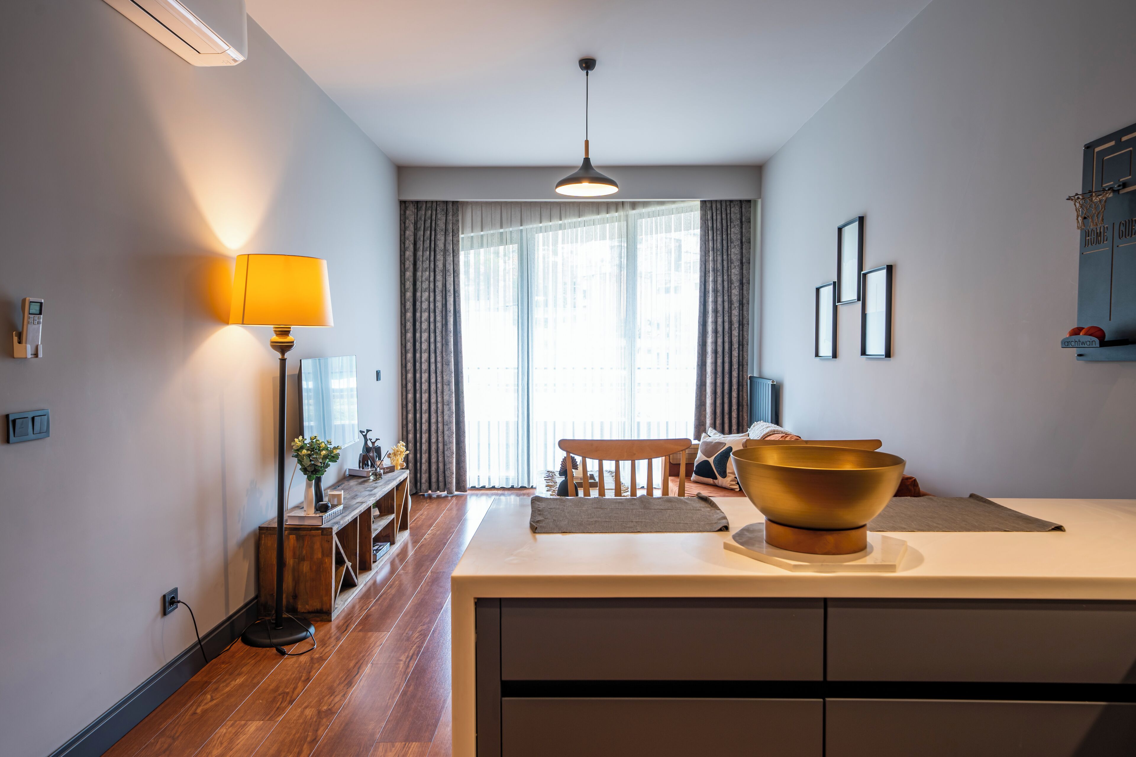 A modern kitchen with a wooden dining table, a large bowl on the counter, and a pendant light.