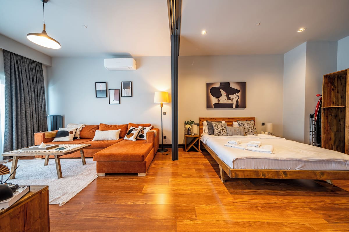 Un dormitorio moderno con suelo de madera, un sofá, una cama y un escritorio.