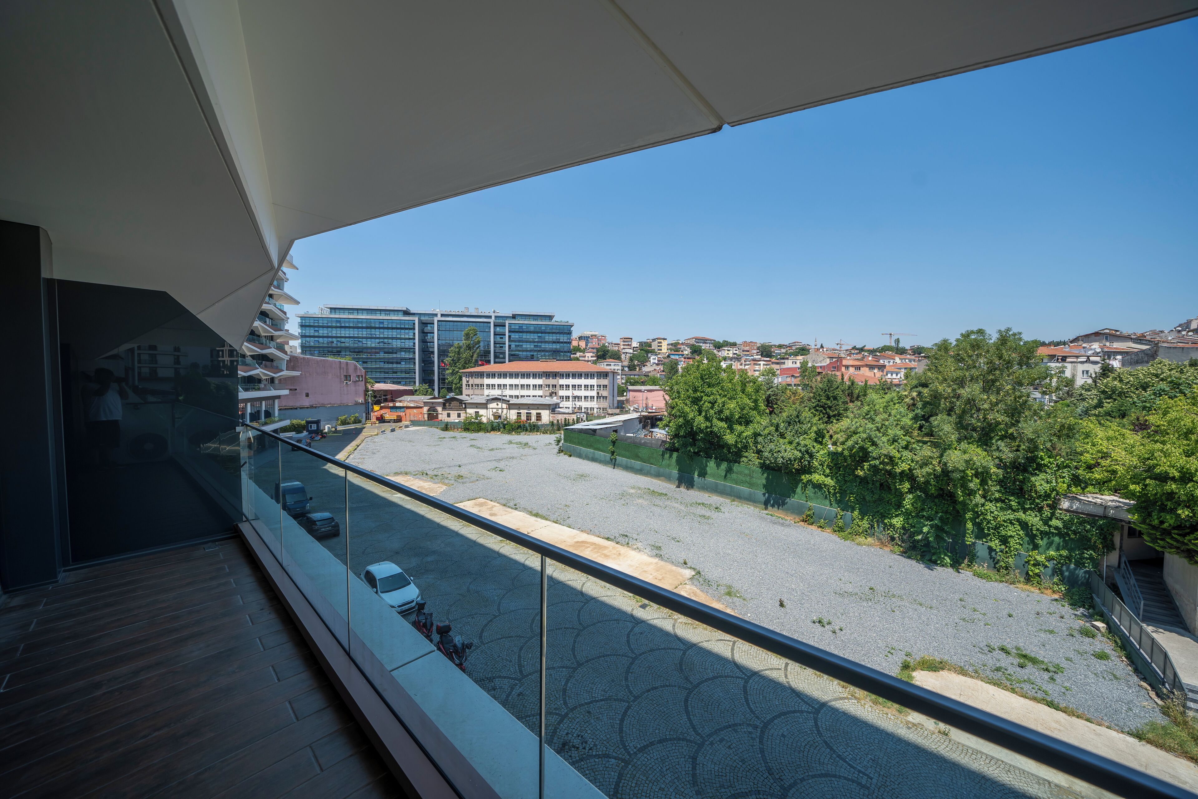 Un balcon offrant une vue dégagée sur un parking, des immeubles et des espaces verts.