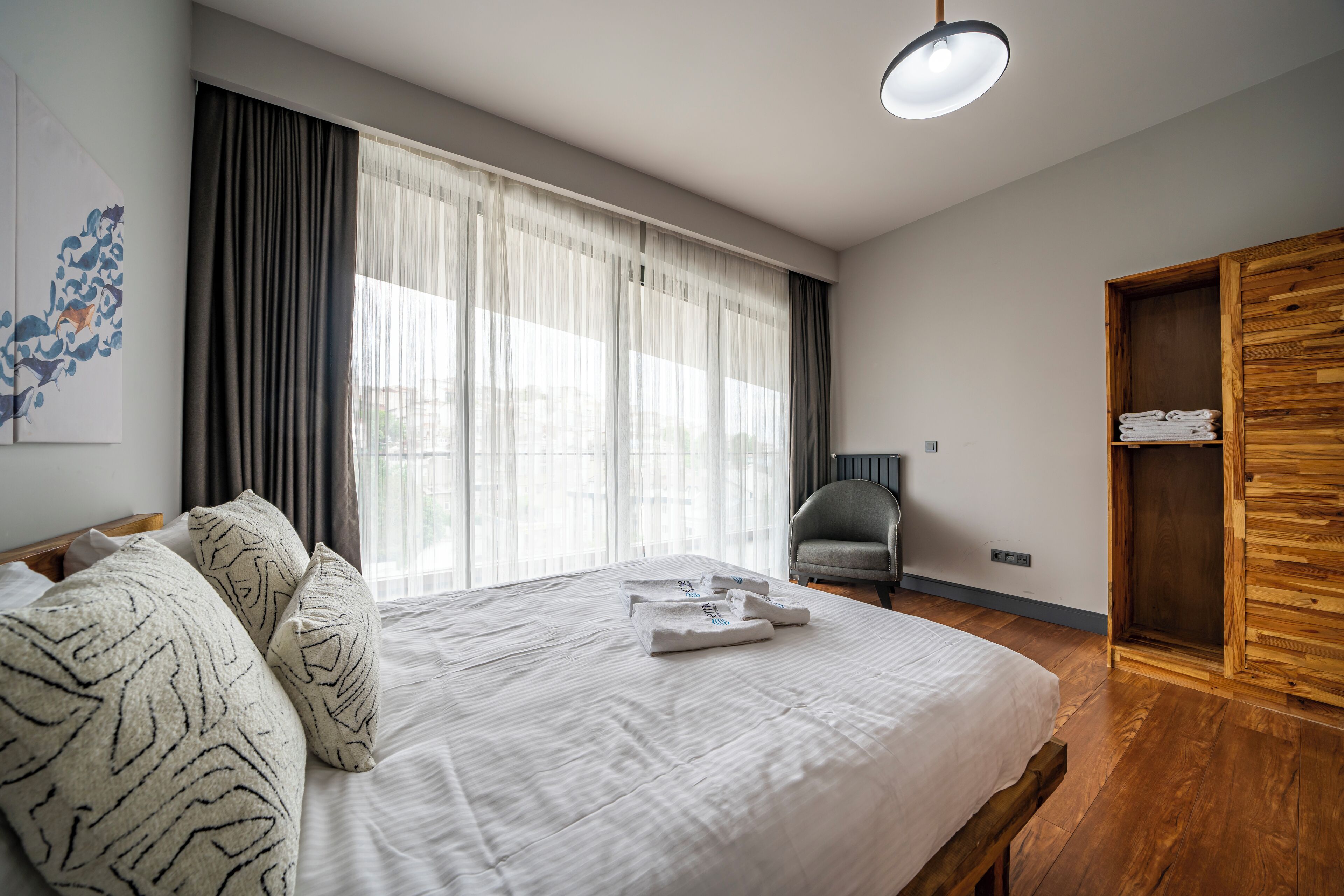 Un dormitorio moderno con una cama grande, un armario de madera y una silla.