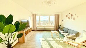 A living room with a TV, sofa, and large plant.