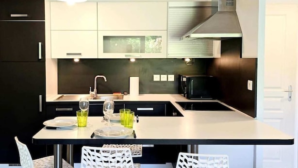 Een moderne keuken met een centraal eiland, zwarte kastjes en een roestvrijstalen afzuigkap.