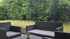 Ein Patio mit Korbmöbeln und einem Glastisch.