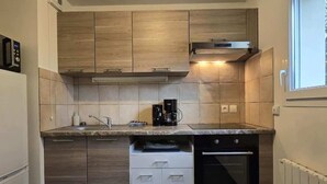Eine kompakte Küche mit Holzausstattung, einem eingebauten Backofen und einer Kaffeemaschine auf der Arbeitsfläche.