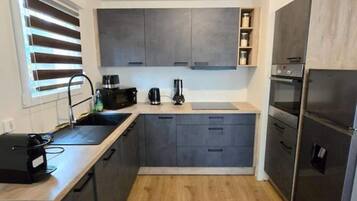 A compact kitchen with grey cabinets, a built-in oven, and a coffee machine.