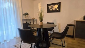 Moderni ruokailutila, jossa on pyöreä pöytä, neljä mustaa tuolia, ruukkukasvi ja seinällä maailmankartta.