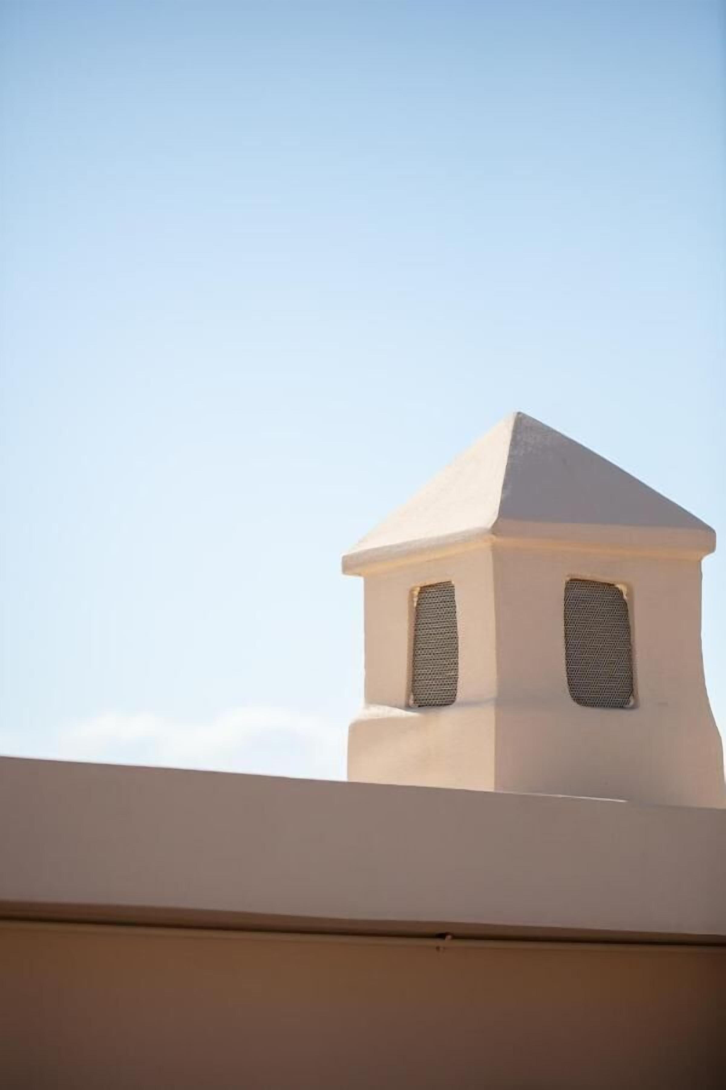 A building with a small, white, pyramid-shaped structure with two windows.
