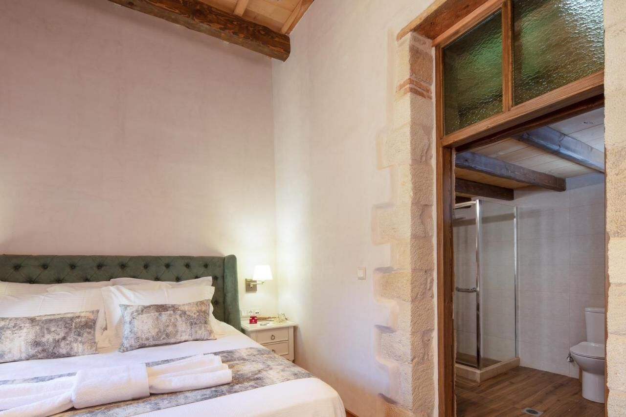 A bedroom with a bed, bedside table, lamp, and a shower area.
