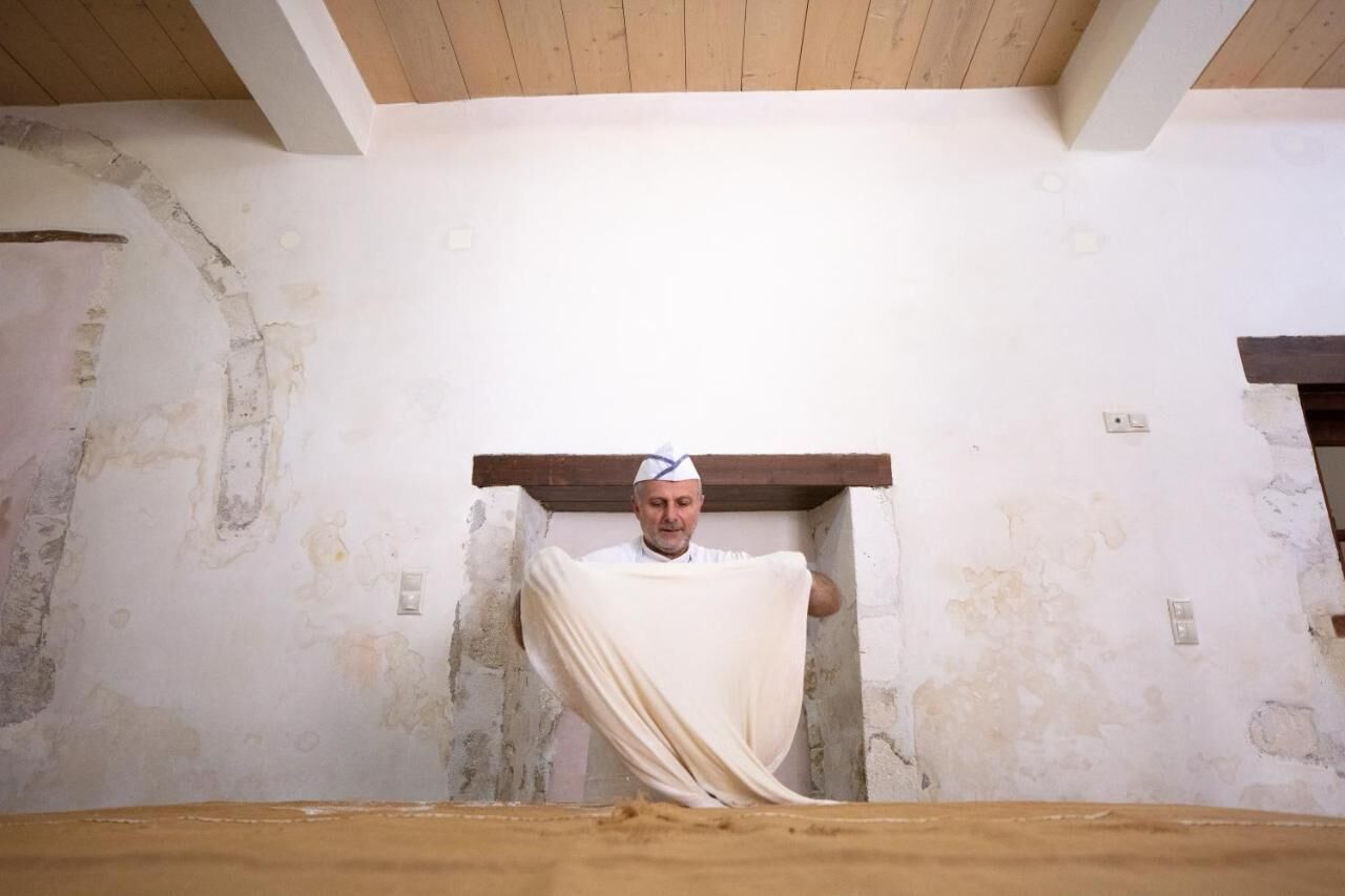 A room with exposed brick walls, a wooden ceiling, and a person standing in a doorway.