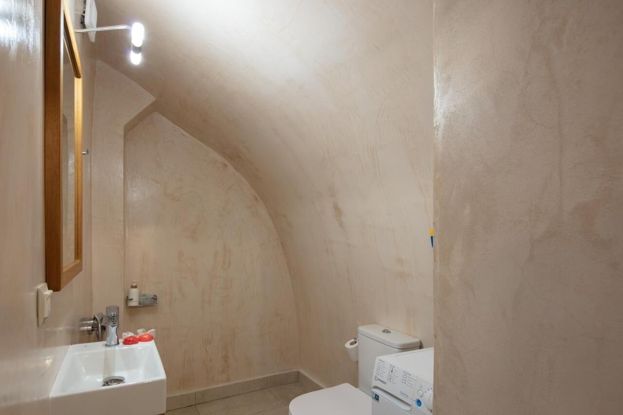 A small, narrow bathroom with a white sink, a toilet, and a shower area.
