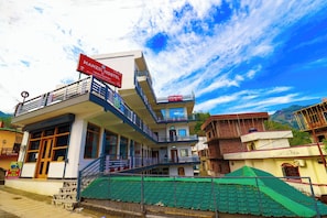 A multi-story building with a sign for Manzil Hostel, featuring balconies and a staircase. - Manzil Hostel (Rishikesh)