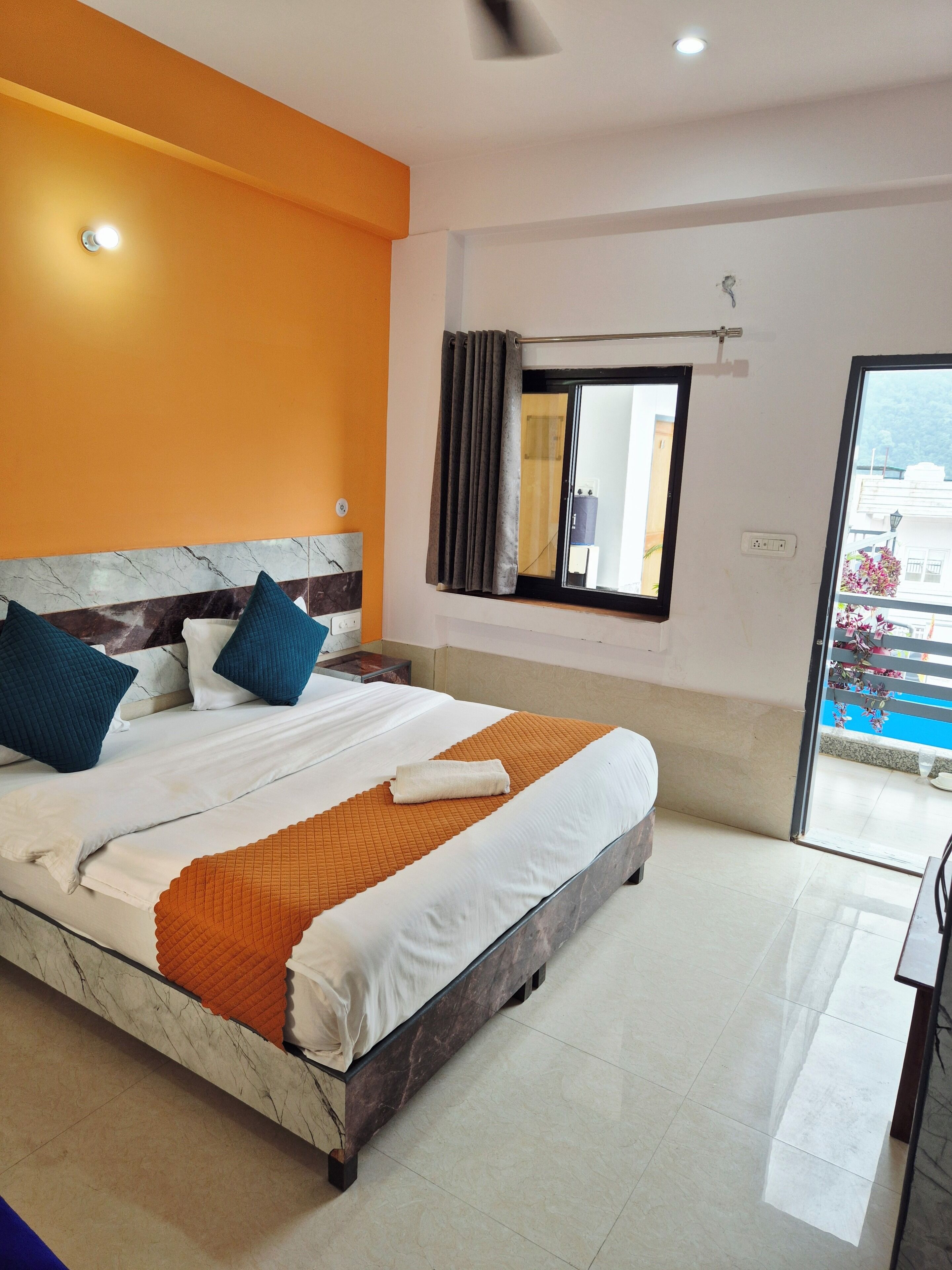 A hotel room with a large bed, a window with curtains, a ceiling fan, and a view of the outside.