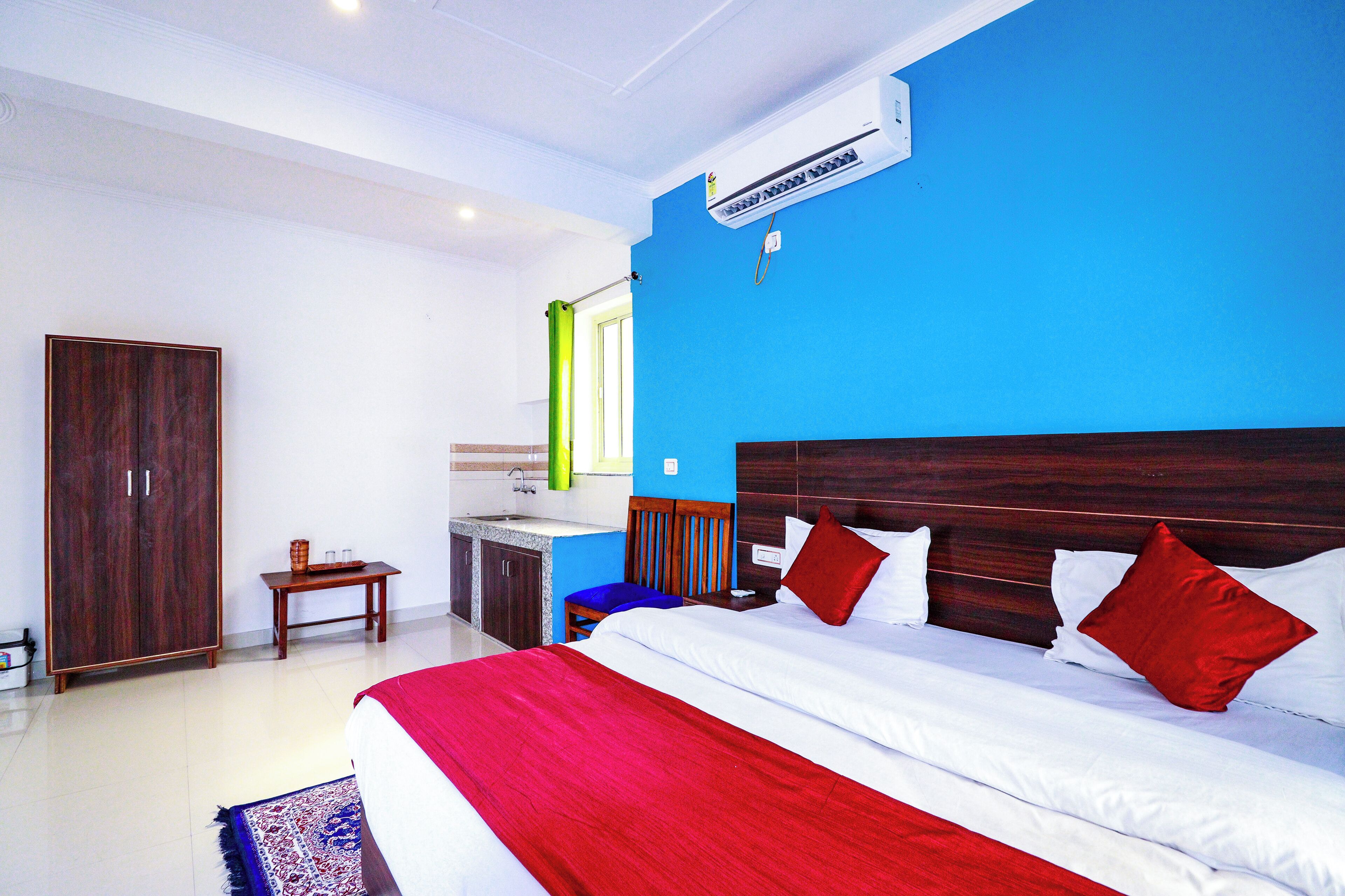 A hotel room with a large bed, a wardrobe, a desk with a chair, and a bathroom.