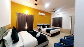 A hotel room with two beds, a ceiling fan, an air conditioning unit, and a window with curtains. - Manzil Hostel (Rishikesh)