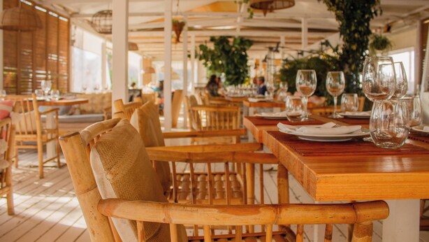 Un restaurante con mesas y sillas de madera, algunas con cojines.