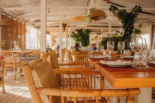 Un restaurante con mesas y sillas de madera, algunas con cojines.