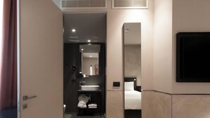 Un baño de hotel moderno con un espejo grande, un lavamanos y un inodoro.