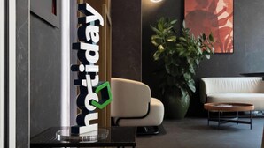Un moderno vestíbulo de hotel con mostrador de recepción, un sofá, una mesa de centro y una gran planta en maceta.