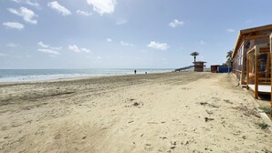 Ein Strand mit einem Rettungsturm, einer Holzkonstruktion und blauem Himmel.