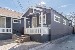 Una casa de dos pisos con un porche delantero, una escalera de ladrillo y un garaje.