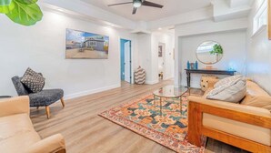 A spacious living room with a ceiling fan, a large rug, and a sofa.