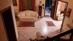 Un soggiorno con un divano, due poltrone, un tavolino da caffè e una scala.