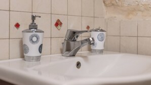 Un lavamanos con grifo de cromo y dispensador de jabón.