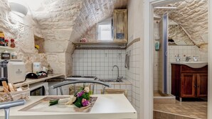 Una cocina compacta con pared de piedra, un ventanal pequeño y un lavamanos.