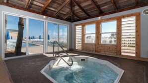 Tinaco con cubierta de madera y vista a una playa a través de amplios ventanales.