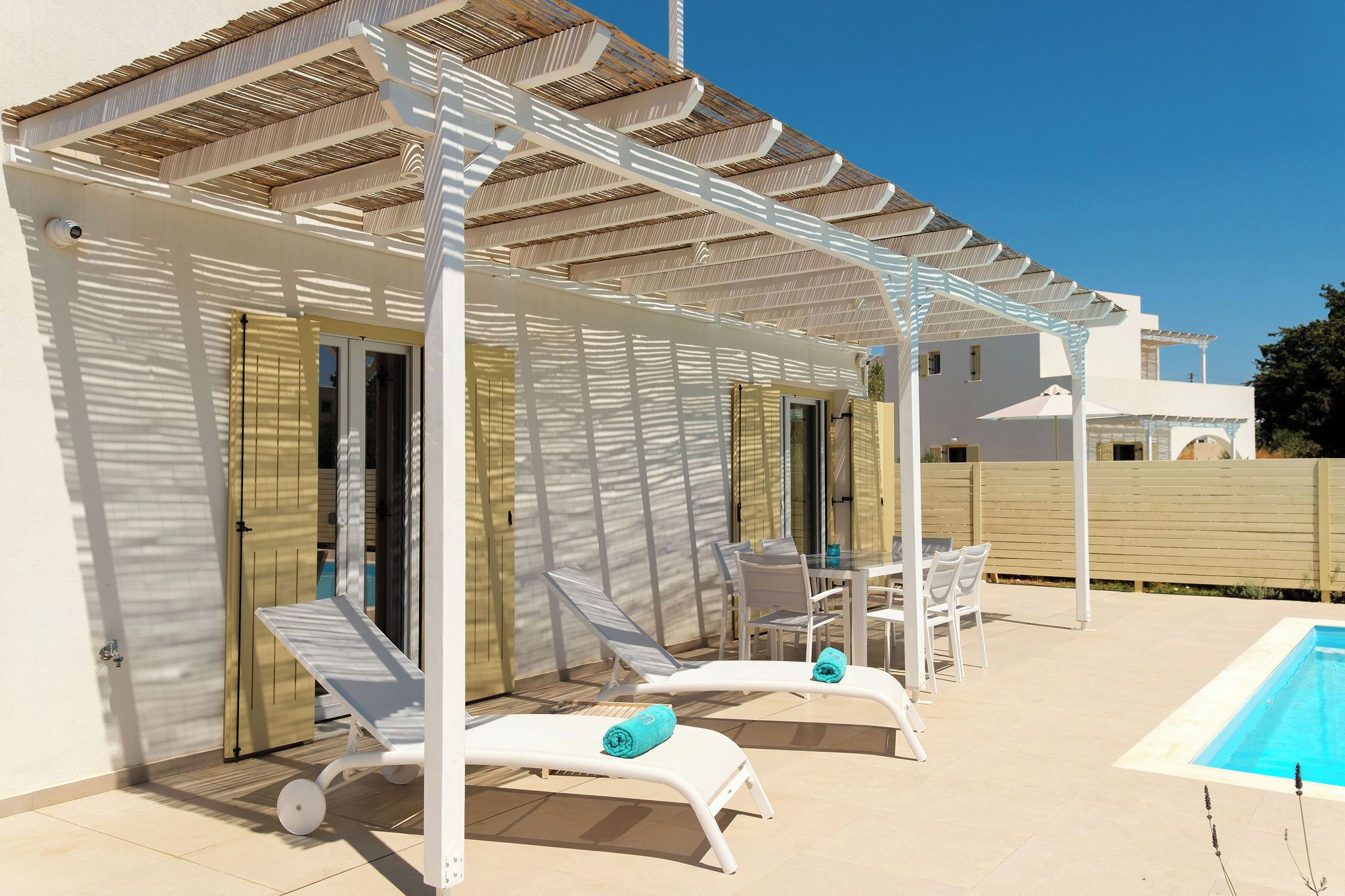 A covered outdoor area with lounge chairs and a pool.