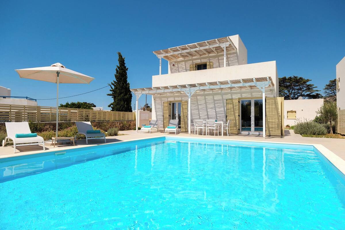A modern pool area with a clear blue pool, lounge chairs, and a covered patio.