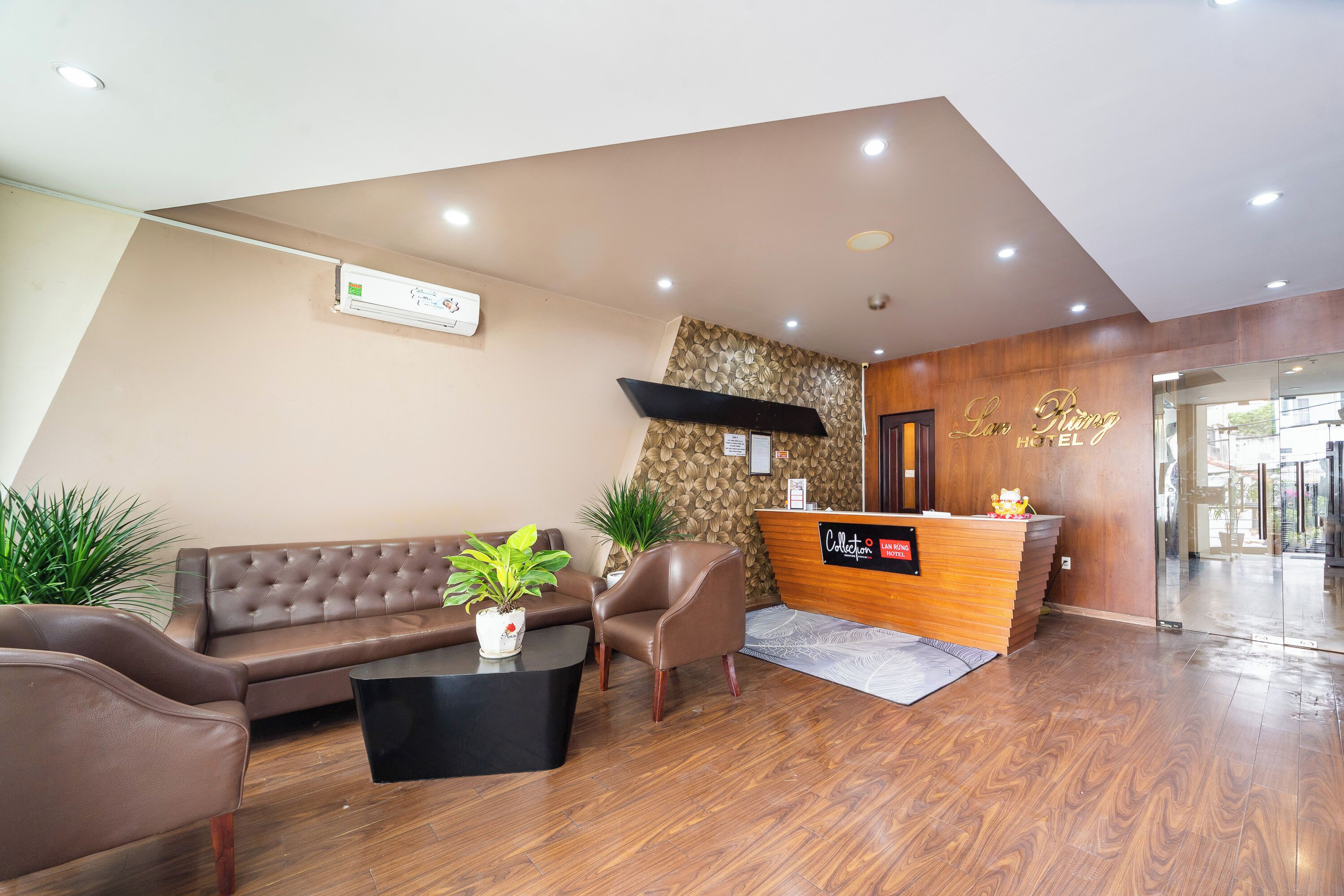 A hotel reception area with a reception desk, a sofa, a chair, and a coffee table.