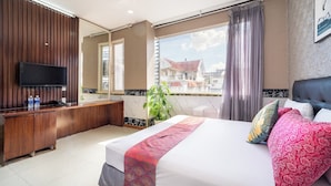 A hotel room with a bed, a TV, a desk, and a window with a view of buildings. - Collection O District 10 Near Van Hanh Hospital Formerly Lan Rung Hotel (Ho Chi Minh City)