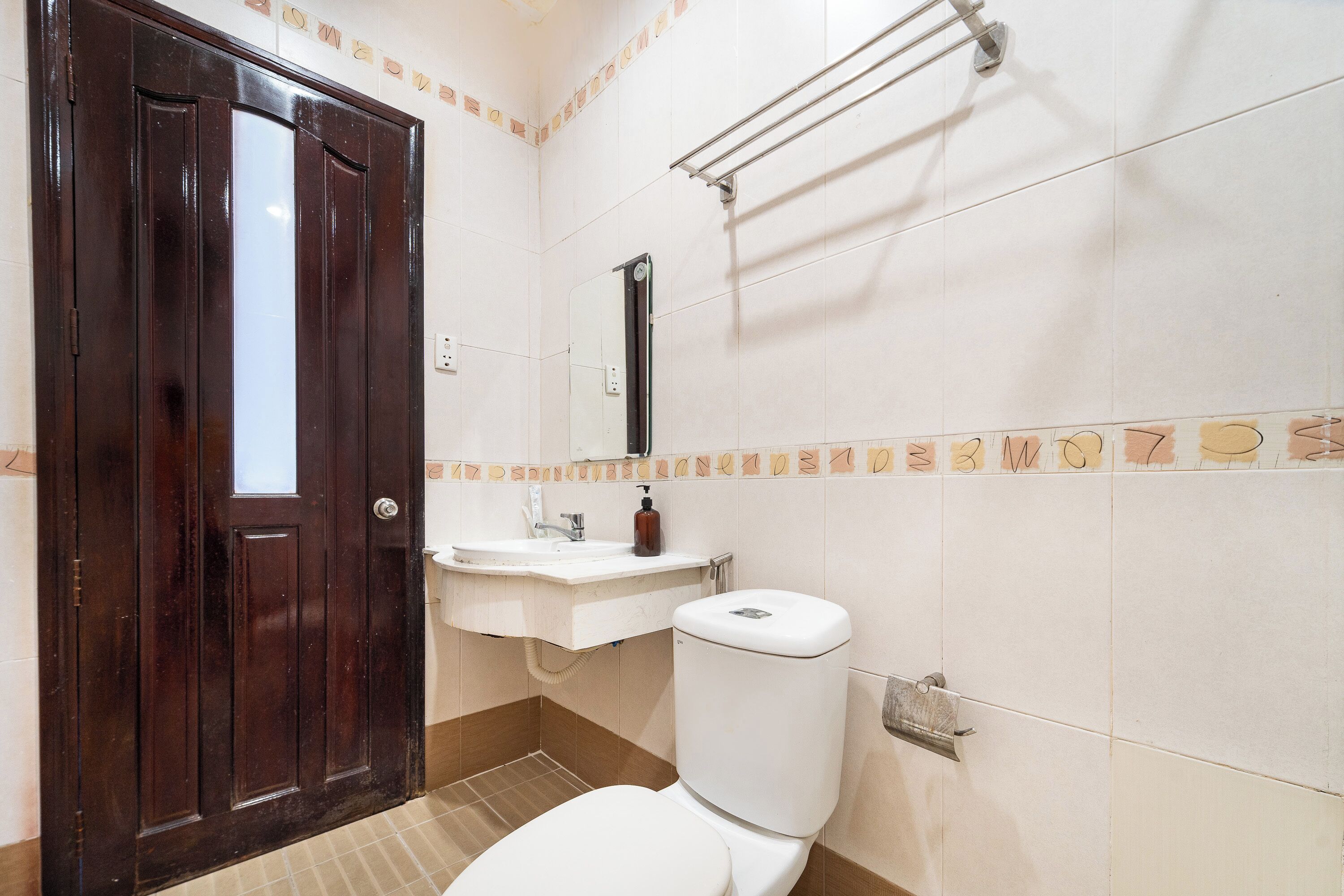 Ein Badezimmer mit Holztür, Toilette, Waschbecken und Handtuchhalter in Weiß.