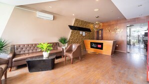 A hotel reception area with a modern design, featuring a reception desk, a leather sofa, and a potted plant. - Collection O District 10 Near Van Hanh Hospital Formerly Lan Rung Hotel (Ho Chi Minh City)