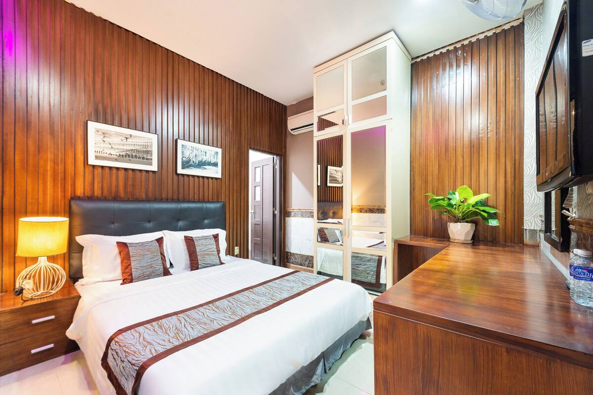 Ein Hotelzimmer mit einem großen Bett, Holzpaneelen, einem Schreibtisch und einem Fernseher.