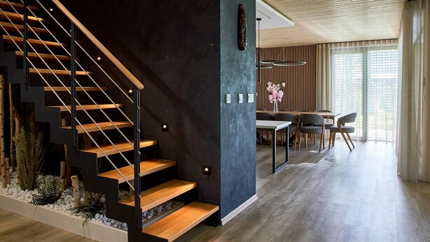 A modern interior with a wooden staircase, a dining area, and a large window with curtains. - Villa Albatros Paradise in the middle of Lauzitzer Gebirge and Golf Resort Malevil (Liberecký kraj)