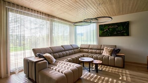 A modern living room with a sectional sofa, a round coffee table, and a painting on the wall. - Villa Albatros Paradise in the middle of Lauzitzer Gebirge and Golf Resort Malevil (Liberecký kraj)