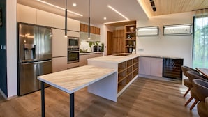 A modern kitchen with a central island, stainless steel appliances, and wooden cabinetry. - Villa Albatros Paradise in the middle of Lauzitzer Gebirge and Golf Resort Malevil (Liberecký kraj)