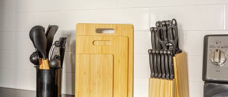 A kitchen counter with a wooden cutting board, a utensil holder, and a toaster.