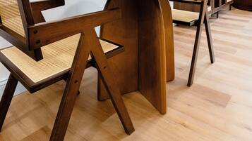 Una habitación moderna con una mesa de comedor y sillas de madera, un espejo grande y un cuadro en la pared.