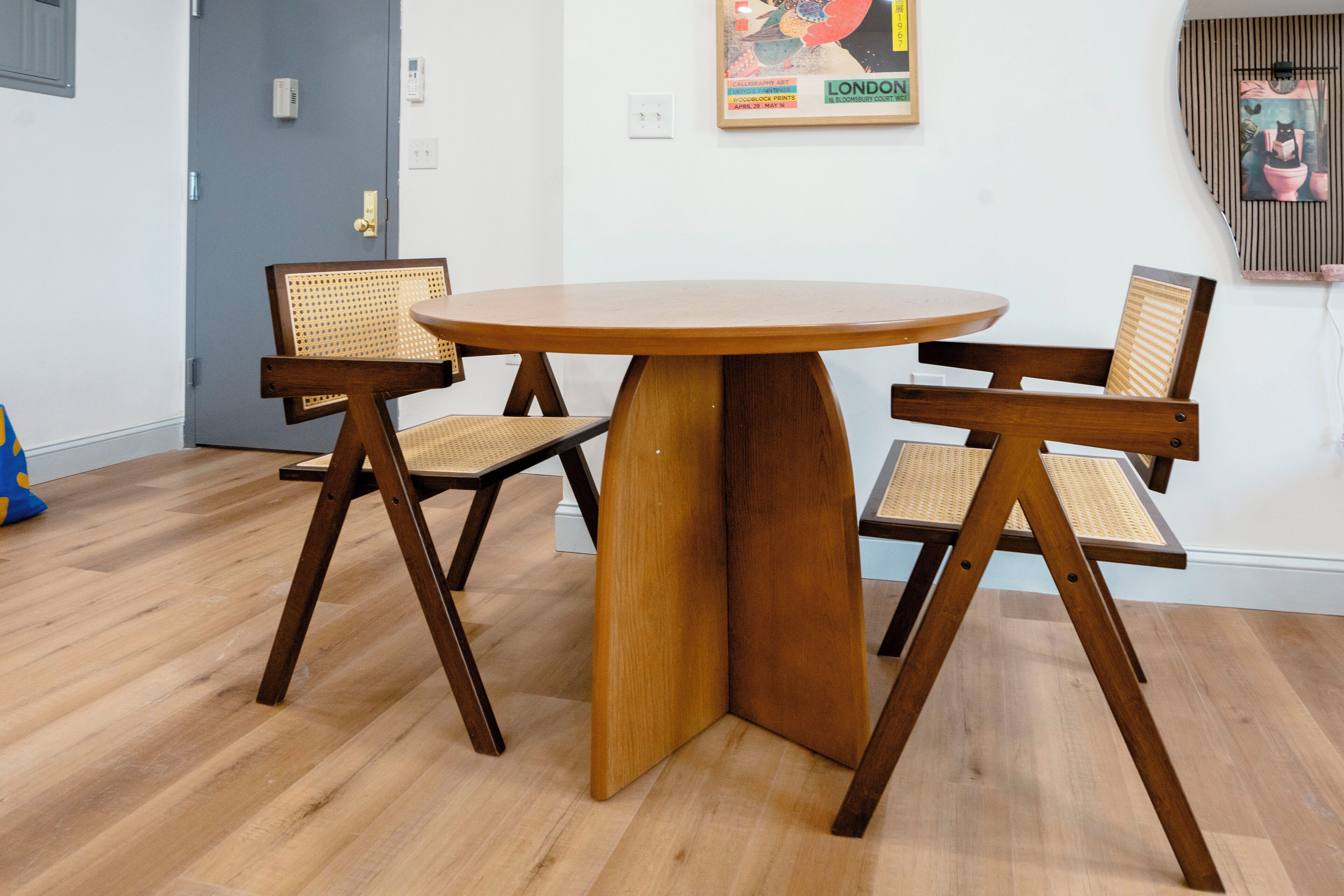 Un comedor con una mesa redonda de madera y cuatro sillas con asientos de mimbre.