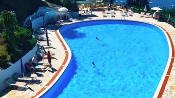 Een buitenzwembad, parasols voor strand/zwembad