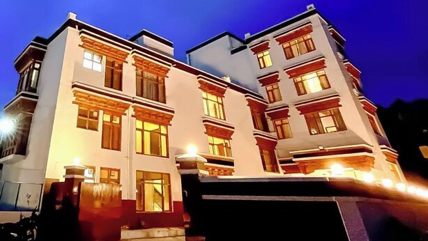 A multi-story building with a symmetrical facade, large windows, and a central entrance. - Royal Hills Ladakh (Leh)