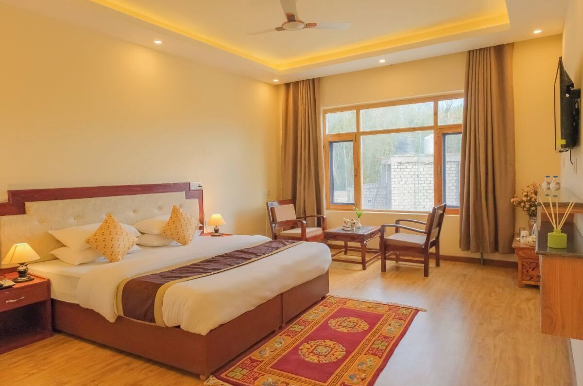 A hotel room with a large bed, a desk, and a chair.