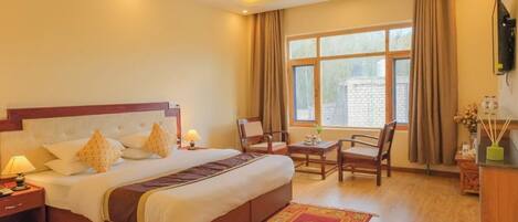 A hotel room with a large bed, a desk, and a chair.