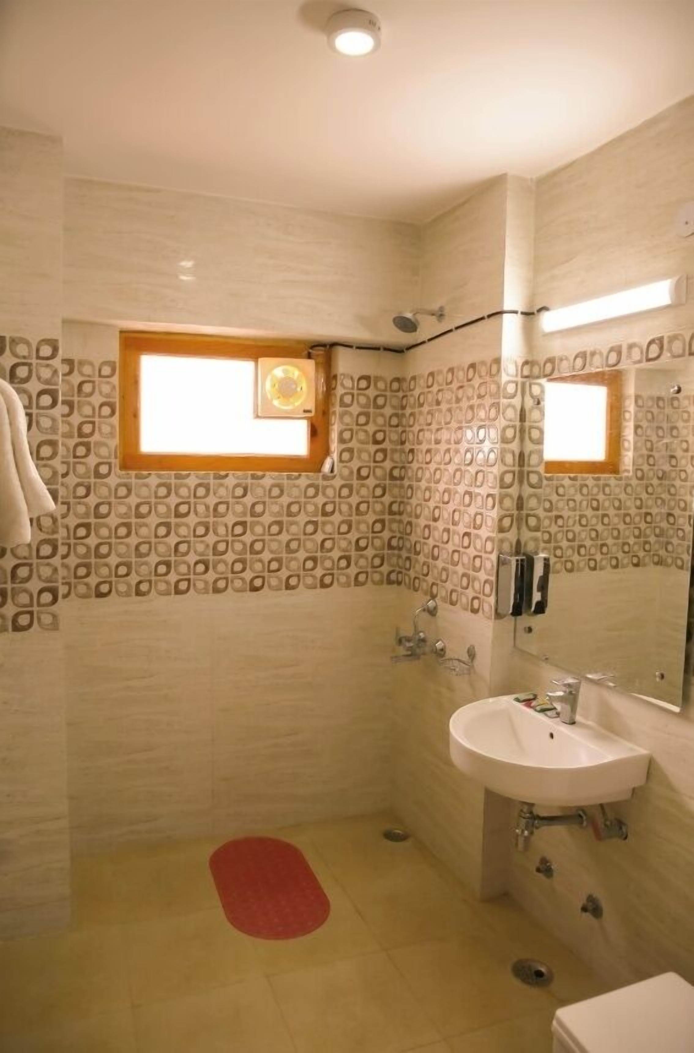 A bathroom with patterned walls, a window, a sink, and a toilet.