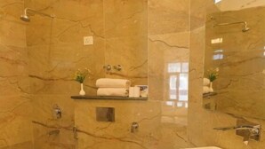 A bathroom with a marble wall, a white toilet, a sink with a marble countertop, and a shower area. - Royal Hills Ladakh (Leh)