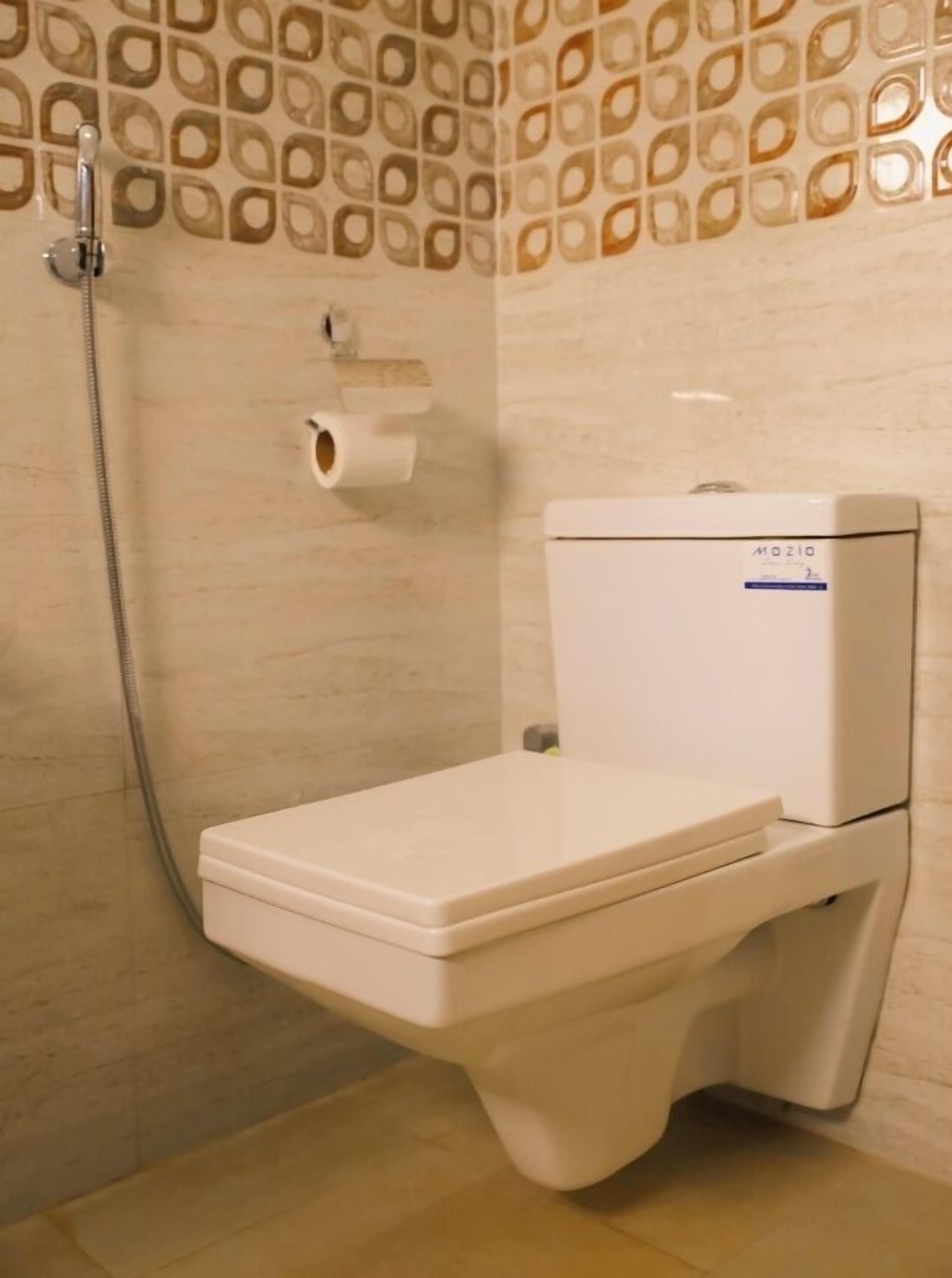 Un baño moderno con inodoro, ducha y un dispensador de papel higiénico en la pared.
